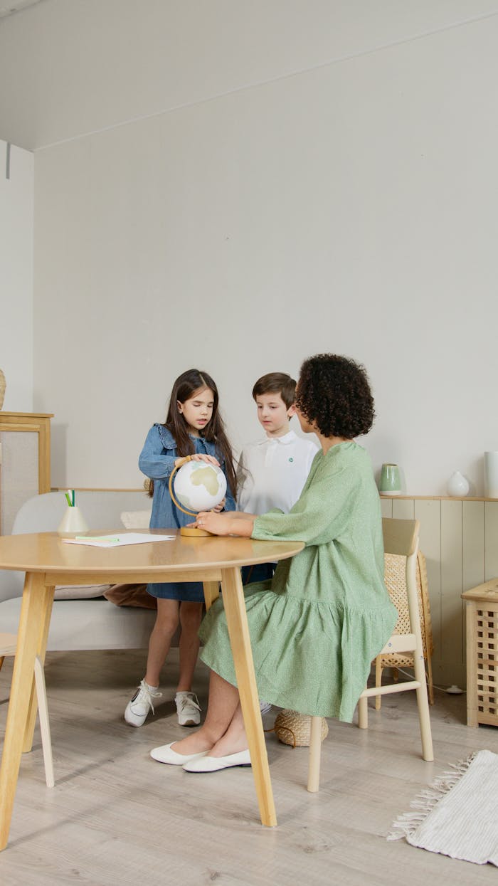 about-us A teacher and two students discussing geography with a globe in a classroom.