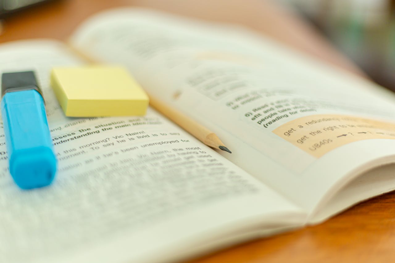 about-us Close-up of an open book with a highlighter and sticky notes for study reference.
